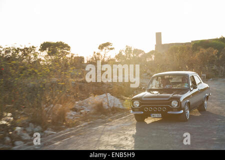 Ford MKI Escort in Malta, schwarzen Auto in Bewegung mit einem natürlichen Sonne Aufflackern Stockfoto