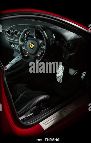 Ferrari F12 in roten Innenaufnahme von Armaturenbrett, Lenkrad, Pedale und Steuerelemente auf einem schwarzen Hintergrund. Stockfoto