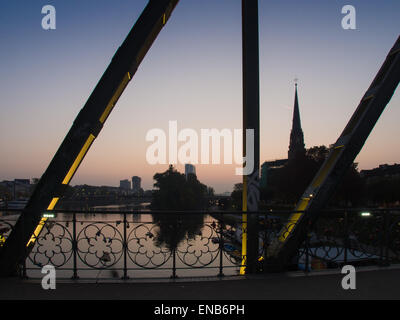 Beleuchtete Eiserner Steg Brücke, Main und Geschäftsgebäude im Zentrum von Frankfurt, Deutschland, bei Sonnenaufgang Stockfoto