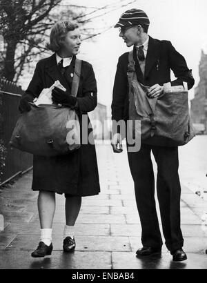 Ein Paperboy und Papergirl, gekleidet in ihren Schuluniformen tragen ihre Taschen voller Zeitungen ihre Papierarbeiten Runde. 14. Dezember 1942. Stockfoto