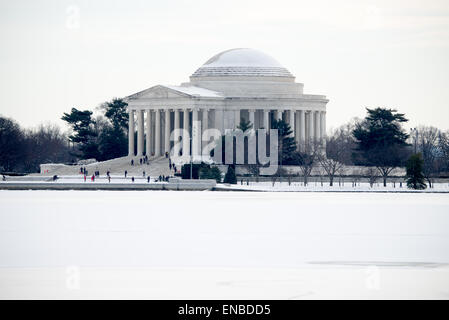 Jefferson Memorial Snow and Ice Washington DC / WASHINGTON, D.C. — Schnee bedeckt das Jefferson Memorial, während Eis das Tidal Basin nach einem Wintersturm bedeckt, die neoklassizistische Kuppel und Säulen stehen in starkem Kontrast zur winterlichen Landschaft. Die Gedenkstätte wurde vom Architekten John Russell Pope entworfen, der nach seinem Tod von den Partnern Otto R. Eggers und Daniel P. Higgins fertiggestellt wurde, und von Präsident Franklin D. Roosevelt am 13. April 1943, dem 200. Geburtstag von Jefferson, eingeweiht. Die runde Kolonnade und die flache Kuppel wurden größtenteils aus weißem Imperial Danby Marmor aus Vermont gebaut Stockfoto