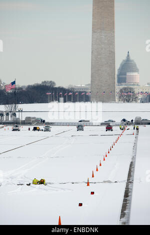 WASHINGTON DC, Vereinigte Staaten – Schnee bedeckt die National Mall, während die Arbeiter weiter am entleerten und schneebedeckten Reflektierenden Pool arbeiten. Stockfoto