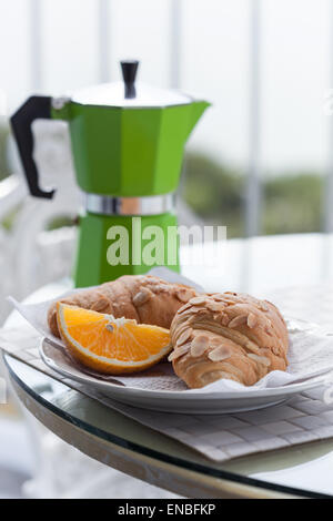 Leckeres Frühstück mit Kaffee auf hoteleigenen Balkon, frische Croissants und Scheibe orange Frucht mit Kaffee Kaffeemaschine staatlich Stockfoto