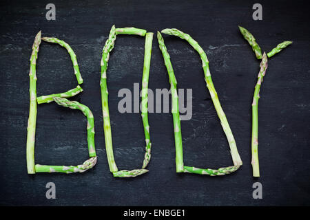 Wort-Korpus aus Spargel Gemüse auf schwarzer Holzplatte. Ansicht von oben. Gesunde Ernährung-Konzept. Stockfoto