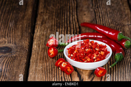 Geschnittene rote Chilis in einer Schüssel (Nahaufnahme) auf hölzernen Hintergrund Stockfoto