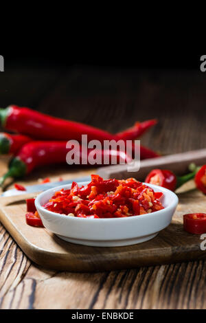 Geschnittene rote Chilis in einer Schüssel (Nahaufnahme) auf hölzernen Hintergrund Stockfoto