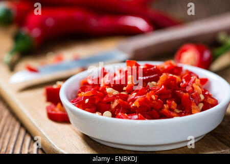 Geschnittene rote Chilis in einer Schüssel (Nahaufnahme) auf hölzernen Hintergrund Stockfoto