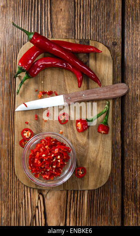 Geschnittene rote Chilis in einer Schüssel (Nahaufnahme) auf hölzernen Hintergrund Stockfoto