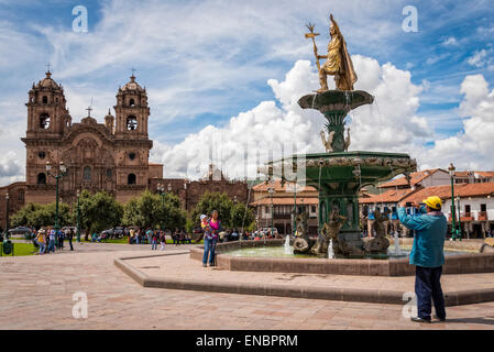 Besucher, die Aufnahme am Brunnen in Plaza de Armas mit La Compañia Kirche im Hintergrund; Cusco. Peru. Stockfoto