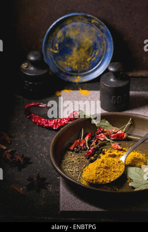 Gewürzen Kurkuma und trockenen Reh hot Chili Peppers auf Metallplatte, Srved über dunklen Tisch mit Vintage Gewicht und blaue Keramik-Platte. Stockfoto