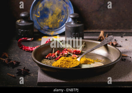 Gewürzen Kurkuma und trockenen Reh hot Chili Peppers auf Metallplatte, Srved über dunklen Tisch mit Vintage Gewicht und blaue Keramik-Platte. Stockfoto