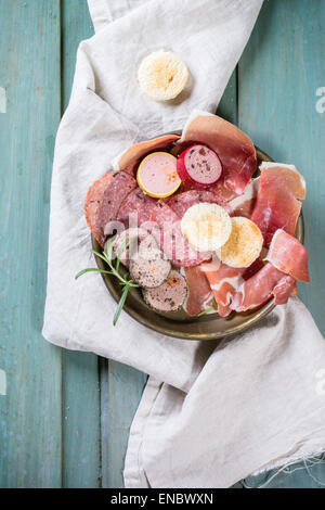 Platte mit Wurst und Pasteten Variation über Türkis Holztisch mit Kräutern und Brot serviert. Draufsicht. Stockfoto