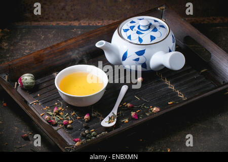 Traditionelle japanische Teekanne und Tasse grüner Tee, serviert auf Bambus-Tablett mit trockenen Tee Variationen über dunklen Hintergrund Stockfoto