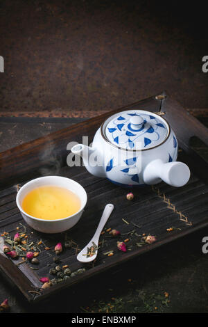 Traditionelle japanische Teekanne und Tasse grüner Tee, serviert auf Bambus-Tablett mit trockenen Tee Variationen über dunklen Hintergrund Stockfoto