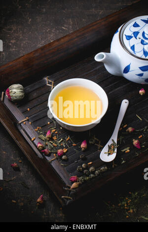 Traditionelle japanische Teekanne und Tasse grüner Tee, serviert auf Bambus-Tablett mit trockenen Tee Variationen über dunklen Hintergrund Stockfoto