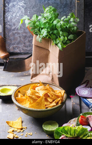 Abendessen im mexikanischen Stil mit Tortilla, Kräuter, Mais-Chips, Nachos und Guakomole, serviert auf grauem Holztisch Stockfoto