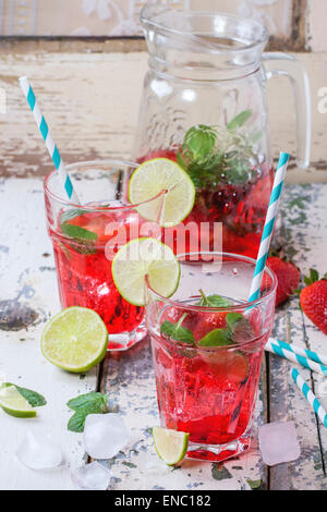 Zwei Gläser mit Retro-cocktail Röhren und Glaskrug mit hausgemachtem Erdbeer Limonade, serviert mit frischen Erdbeeren, Minze, Limette Stockfoto