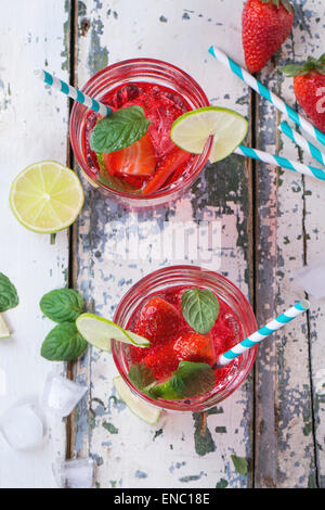 Zwei Gläser mit Retro-cocktail Röhren und Glaskrug mit hausgemachtem Erdbeer Limonade, serviert mit frischen Erdbeeren, Minze, Limette Stockfoto