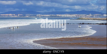Surfer in Costa de Caparica mit Lissabon im Hintergrund. Kultige Location für Surf weil es ein Pionier Strand und Qualität der Wellen Stockfoto
