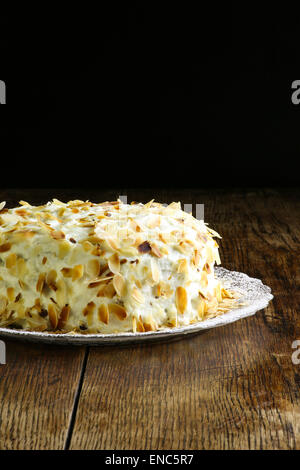 Hausgemachter Karottenkuchen auf Glasplatte mit Sahnehäubchen, alte raue Eichentisch und dunklem Hintergrund, Textfreiraum Stockfoto