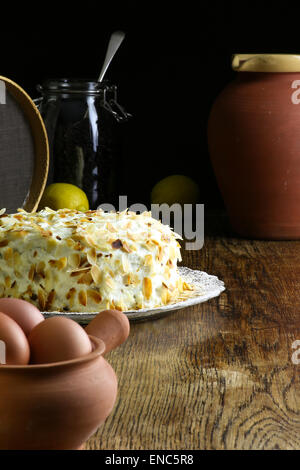 Hausgemachter Karottenkuchen auf Glasplatte mit Puderzucker, frische Eiern im Tontopf, Glas Glas alt grobe Eichentisch und dunklem Hintergrund, Kopie Stockfoto