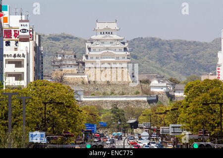 Blick von Himeji Station entlang Ootemae-dori, die breite Hauptstraße, die durch die Stadt zu der Burg hoch aufragt gegen den Wald und blauen Himmel. Stockfoto