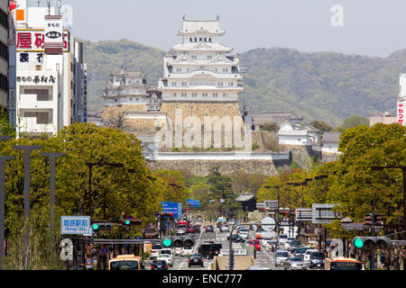 Blick von Himeji Station entlang Ootemae-dori, die breite Hauptstraße, die durch die Stadt zu der Burg hoch aufragt gegen den Wald und blauen Himmel. Stockfoto