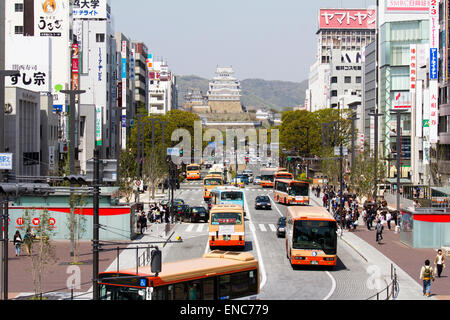 Blick von Himeji Station entlang Ootemae-dori, die breite Hauptstraße, die durch die Stadt zu der Burg hoch aufragt gegen den Wald und blauen Himmel. Stockfoto