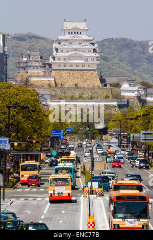 Blick von Himeji Station entlang Ootemae-dori, die breite Hauptstraße, die durch die Stadt zu der Burg hoch aufragt gegen den Wald und blauen Himmel. Stockfoto