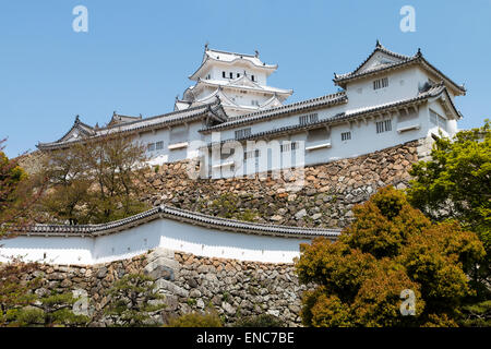 Der Ri-no-Ichi Watari Yagura, Turm, auf der Oberseite der ineinandergreifenden Ishigaki Steinmauern mit Himeji Burg halten hoch über unter einem blauen Himmel. Stockfoto