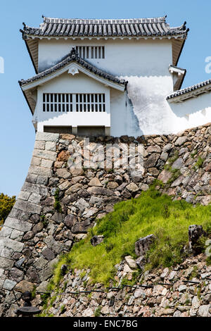 Der Ri-no-Ichi Watari Yagura, Turm, mit Stein Fallloch, Ishi-otoshi, auf abfallenden ishigaki ineinandergreifenden Steinmauern bei Himeji Burg. Blauer Himmel. Stockfoto