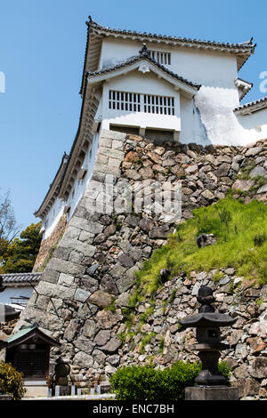 Der Ri-no-Ichi Watari Yagura, Turm, mit Stein Fallloch, Ishi-otoshi, auf abfallenden ishigaki ineinandergreifenden Steinmauern bei Himeji Burg. Blauer Himmel. Stockfoto