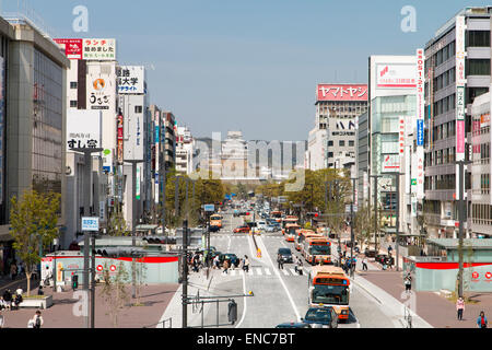 Blick von Himeji Station entlang Ootemae-dori, die breite Hauptstraße, die durch die Stadt zu der Burg hoch aufragt gegen den Wald und blauen Himmel. Stockfoto