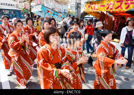 Ein Team reifer Frauen in Kimono-Kleidung singt und tanzt unter den Kirschblüten während der jährlichen Genji-Parade im Frühling in Tada in Japan. Stockfoto