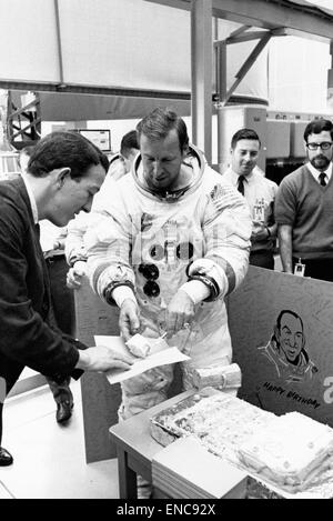 Astronaut Jim Lovell in einem Raumanzug während einer Feier im Weltraum, serviert Geburtstagskuchen. Das Foto zeigt den menschlichen Aspekt von Weltraummissionen und die Kameradschaft unter Astronauten. Stockfoto