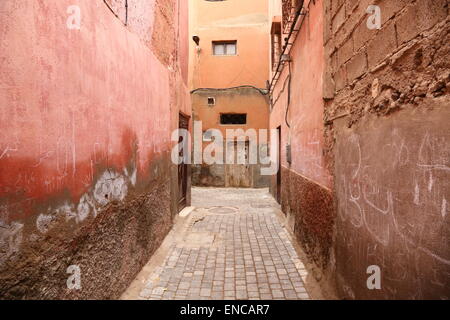 Rote Wände, eine Tür und Kreide Graffiti in einer schmalen Seitenstraße in der Medina, Marrakesch, Marokko Stockfoto