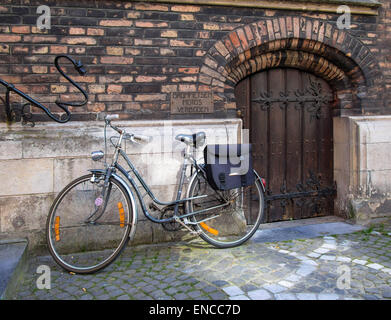 BRÜGGE, BELGIEN, Großbritannien - 13. APRIL 2014: Fahrrad neben der alten Tür geparkt Stockfoto