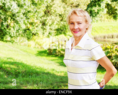 Porträt einer Frau mittleren Alters in einem Park an einem sonnigen Tag Stockfoto