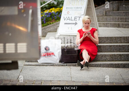 "Downtown Atlanta Georga USA Dame ruht auf dem Bürgersteig im roten Kleid SMS Surfen im Internet auf ihrem iPhone Stockfoto