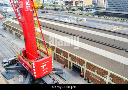 Arbeitnehmer unter einem Liebherr Kran im Hafen von Kapstadt, Südafrika Stockfoto