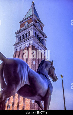 29. April 2015 - Venedig, Provinz Venedig, Italien - an der Loggia über der Vorhalle der Basilika von St. Markus, blickt eine Nachbildung eines der vier legendären Bronze Pferde von San Marco auf den Campanile di San Marco (Glockenturm) in der Piazza San Marco (Markusplatz entfernt). Dort befinden im Jahre 1204 nach der Plünderung Konstantinopels, sich die Originalskulpturen jetzt im Inneren des St.-Markus zum Zwecke der Bestandserhaltung, mit Repliken in ihrer Position auf der Loggia. Venedig, ein UNESCO-Weltkulturerbe zählt zu den beliebtesten internationalen Reisezielen. (Kredit-Bild: © Arnold Drapkin/ZUM Stockfoto