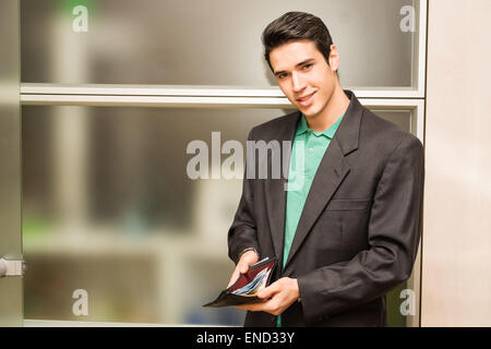 Junger Geschäftsmann im Büro zeigt volle Brieftasche Stockfoto
