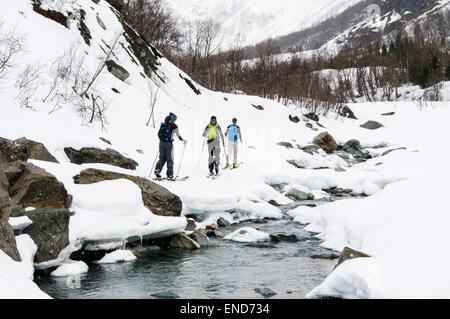 Skifahrer Skitouren entlang eines Flusses im Schnee auf dem Weg nach oben Daltinden, Lyngen Alpen (Lyngsalpene), Troms, Norwegen. Stockfoto