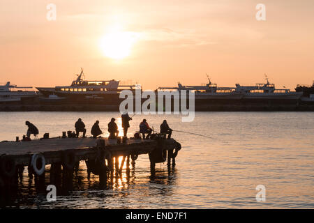 Acht Männer sind auf dem Pier im Sunrise Angeln. Stockfoto