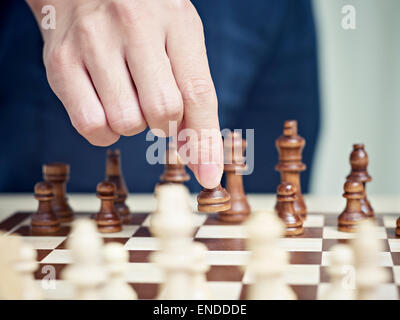 Hand bewegt eine Schachfigur Stockfoto