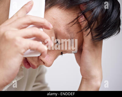 junger Mann sucht traurig und deprimiert während des Gesprächs auf Handy Stockfoto