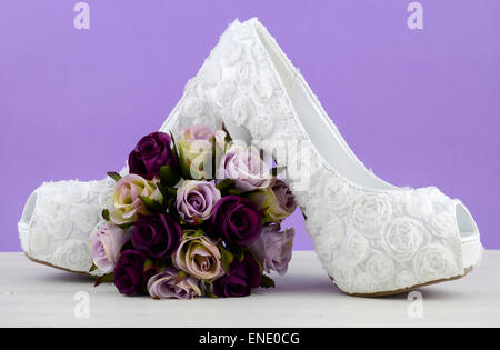 Hochzeit-Theme Weiß floral Brautschuhe mit Blumen auf shabby chic weißen Tisch und lila Hintergrund. Stockfoto