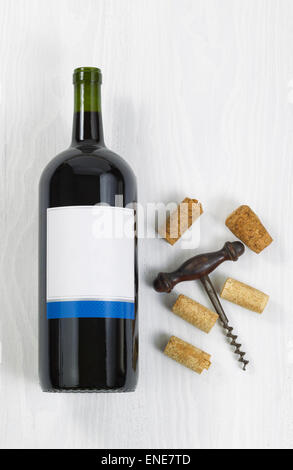 Vertikale Bild eine große Flasche Rotwein mit einem antiken Korkenzieher mit alten Korken auf weißem Holz. Stockfoto