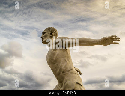 Weiße steinerne Statue eines Mannes laufen in den Wolken Stockfoto