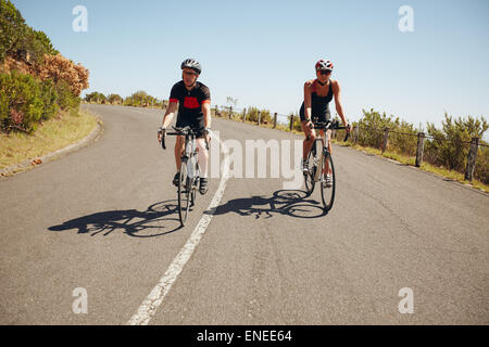 Radfahrer fahren auf eine szenische Landstraße. Triathleten, die Rennen mit dem Fahrrad auf einer Landstraße Stockfoto